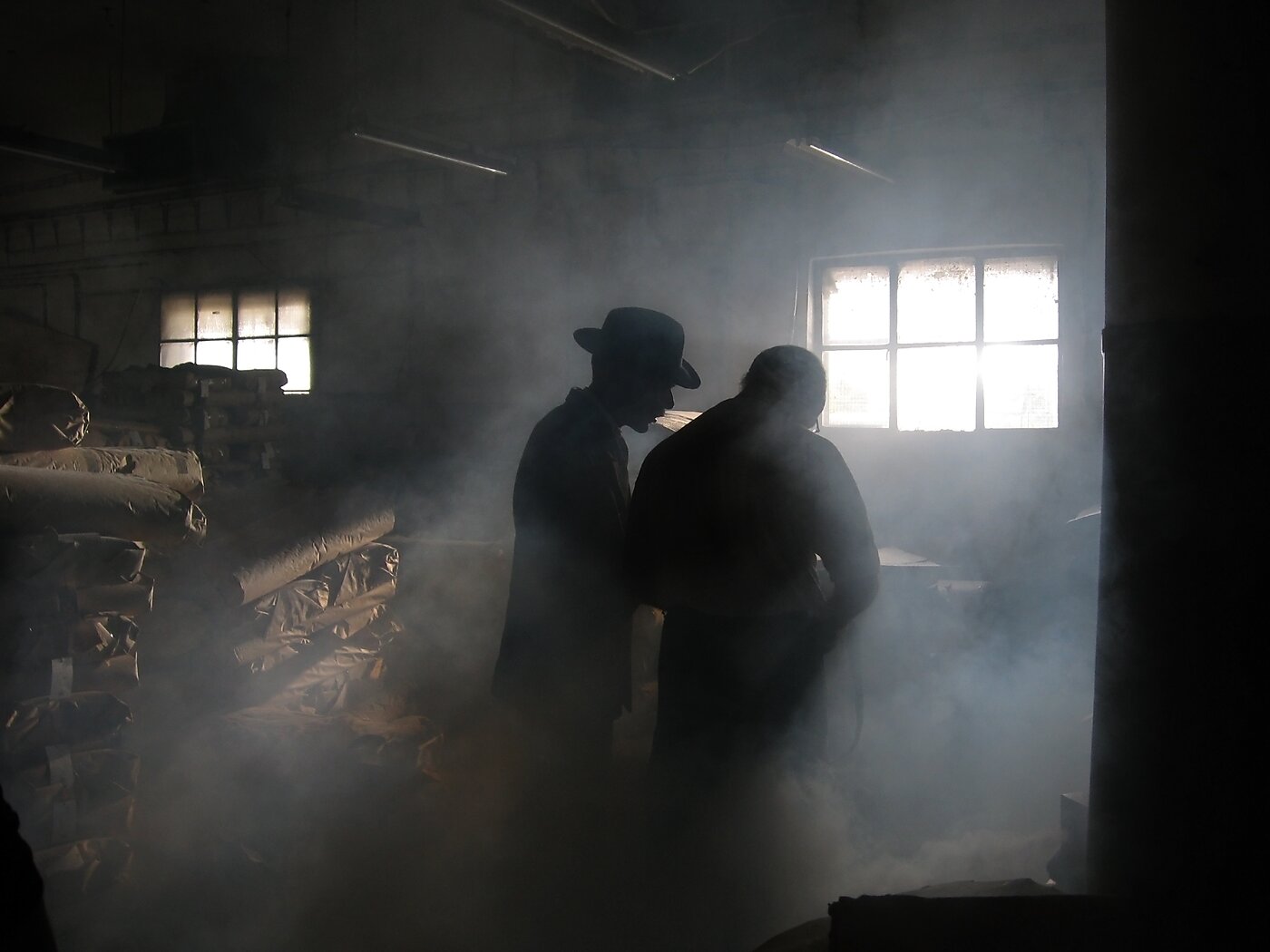 Two silhouettes meet in a smoky room